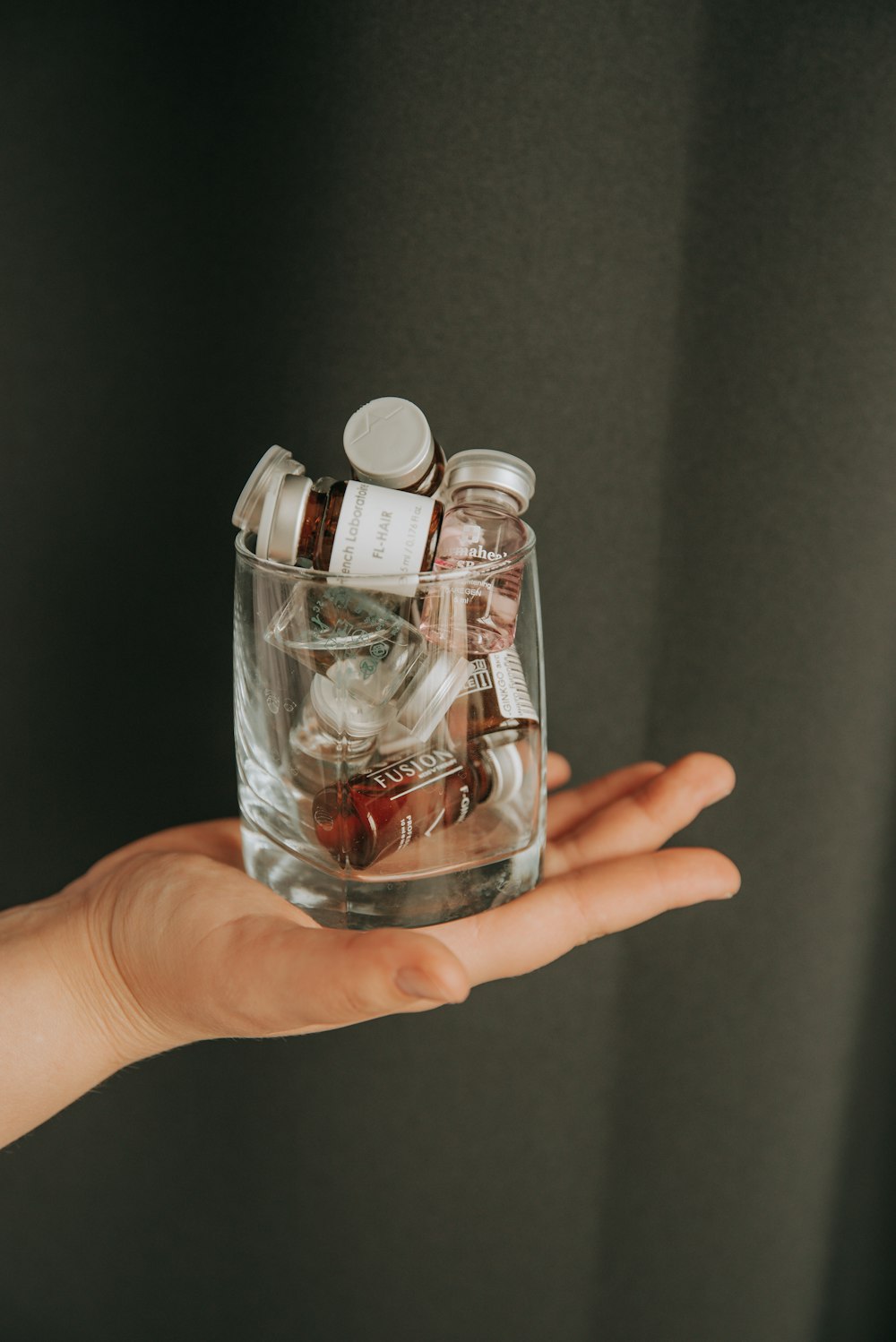 person holding clear glass bottle with red liquid
