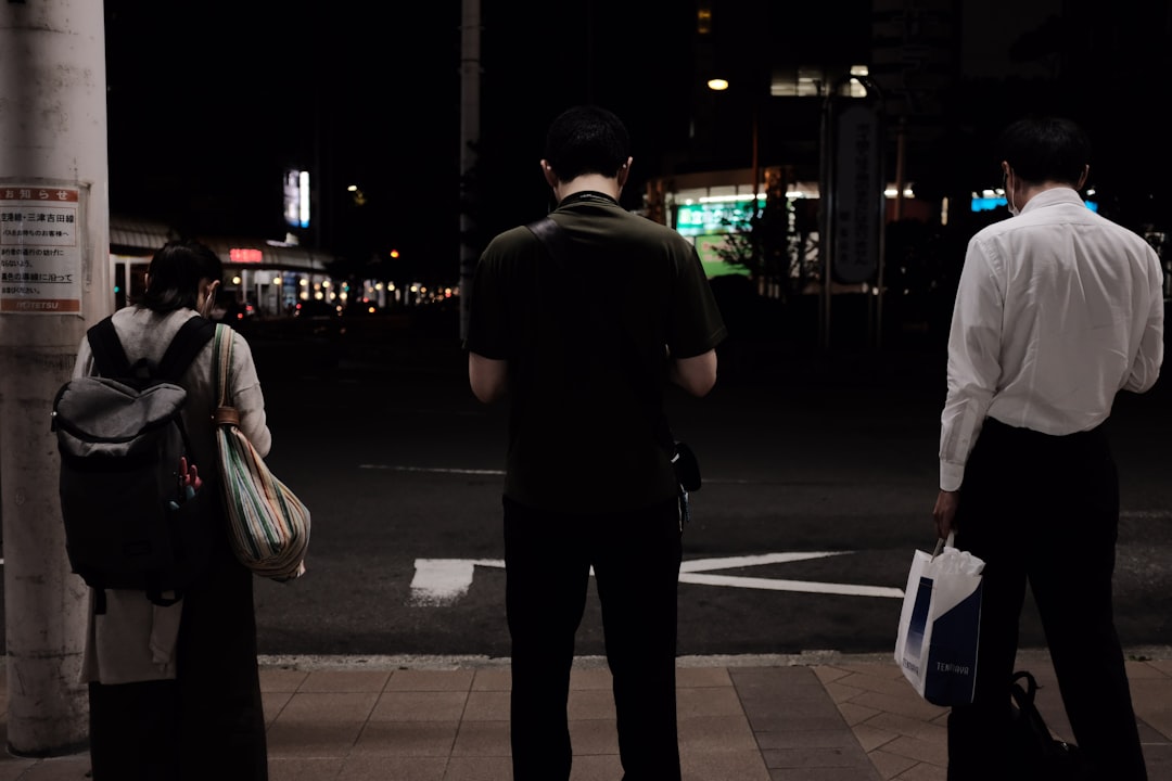 man in black shirt and pants standing on sidewalk during night time