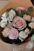 A lush mixed bouquet featuring roses, lilies, and carnations, wrapped in soft pastel paper.