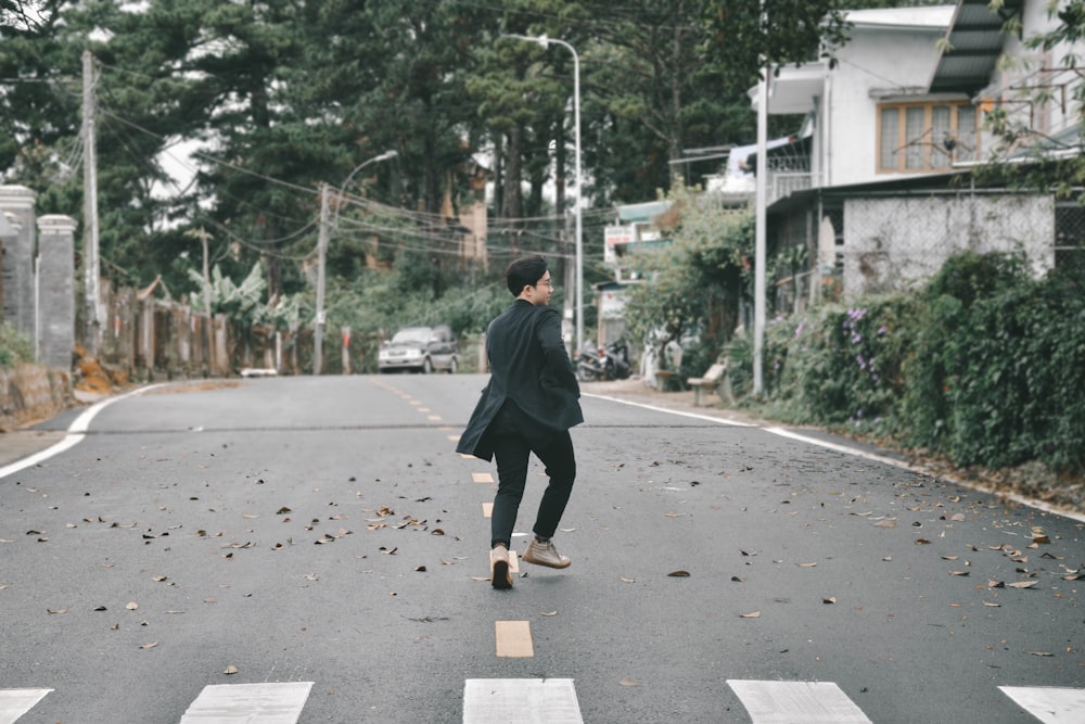 man in black jacket walking on sidewalk during daytime