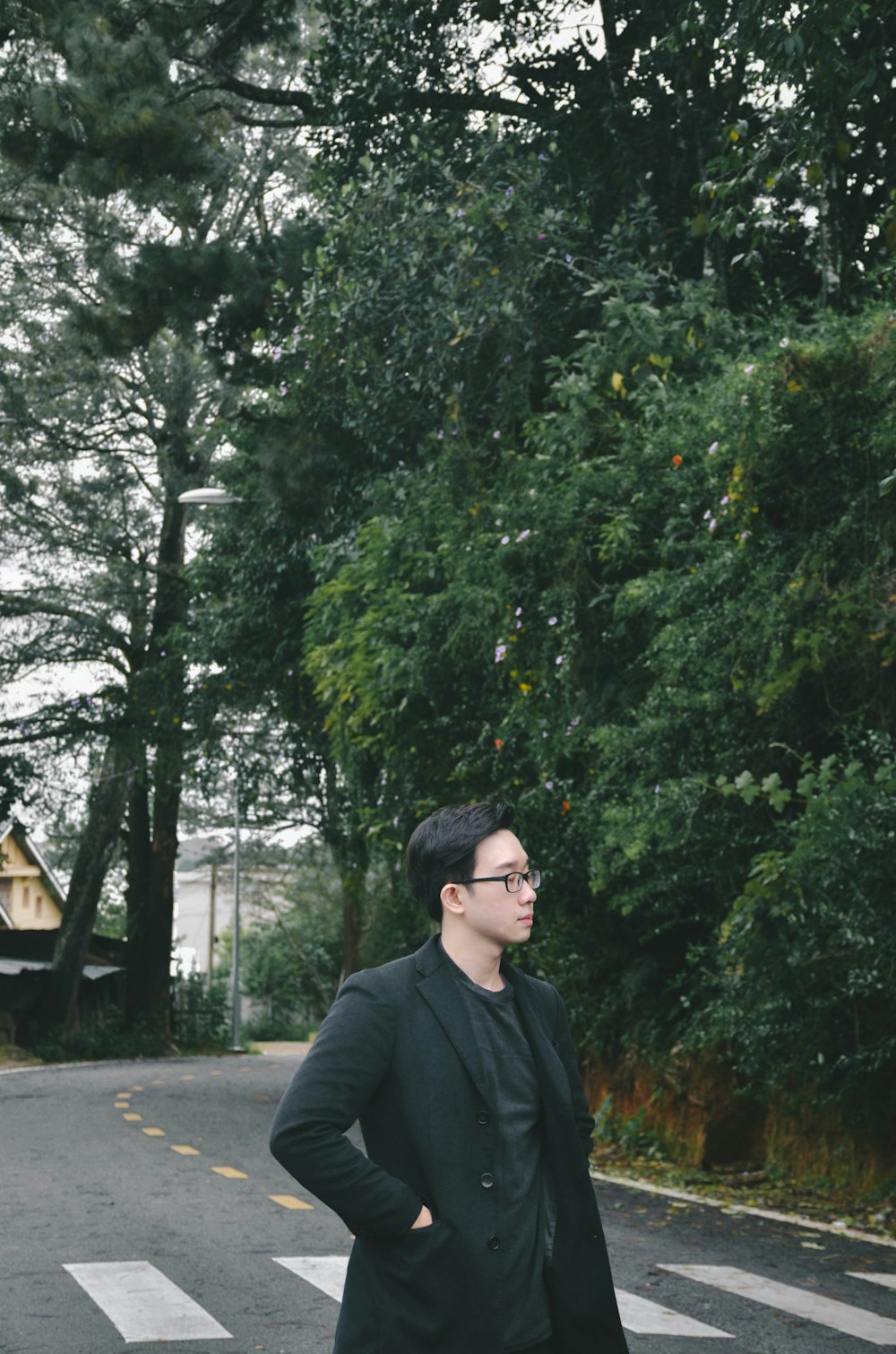 man in black jacket standing near green trees during daytime