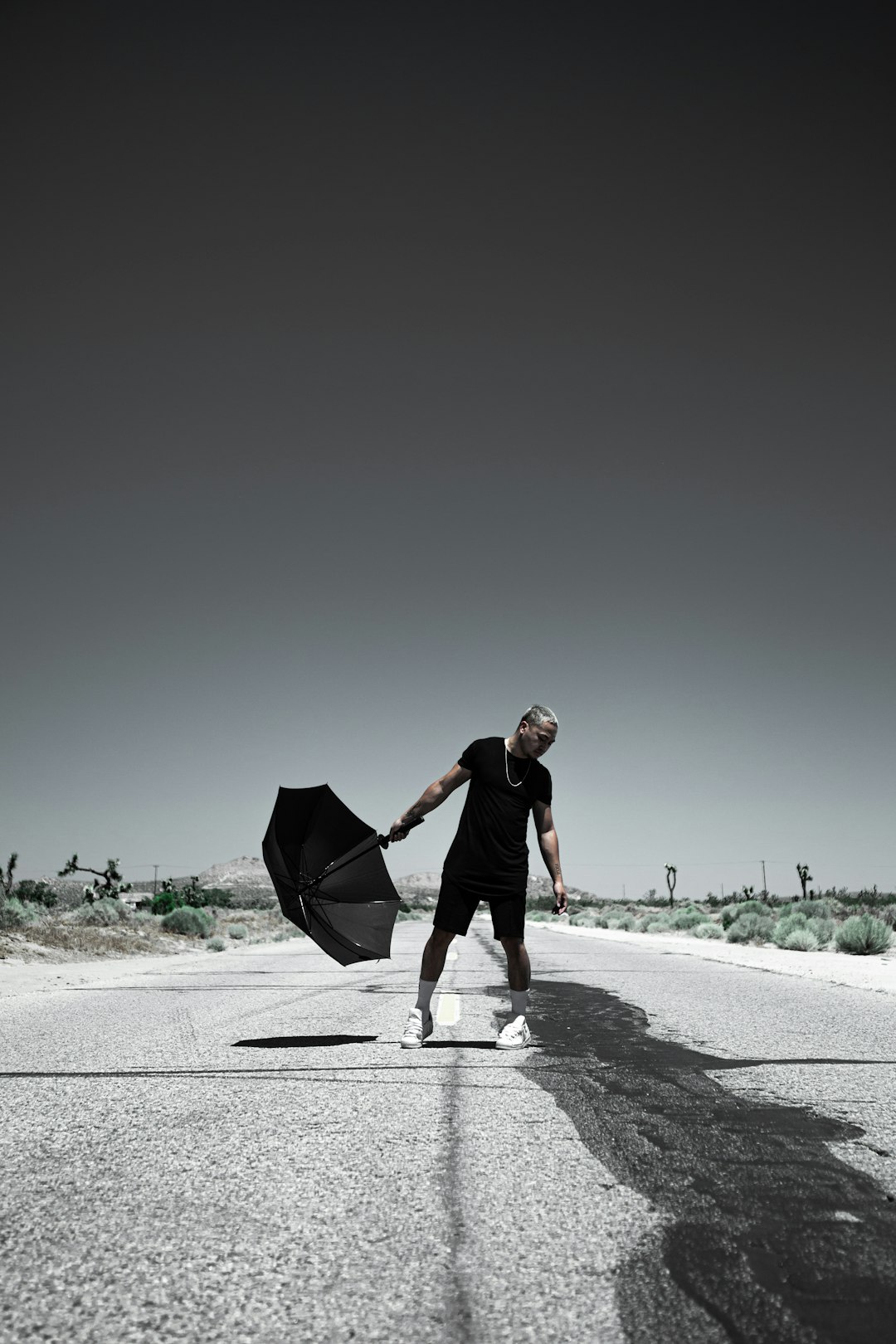 man in black shirt holding umbrella walking on road during daytime