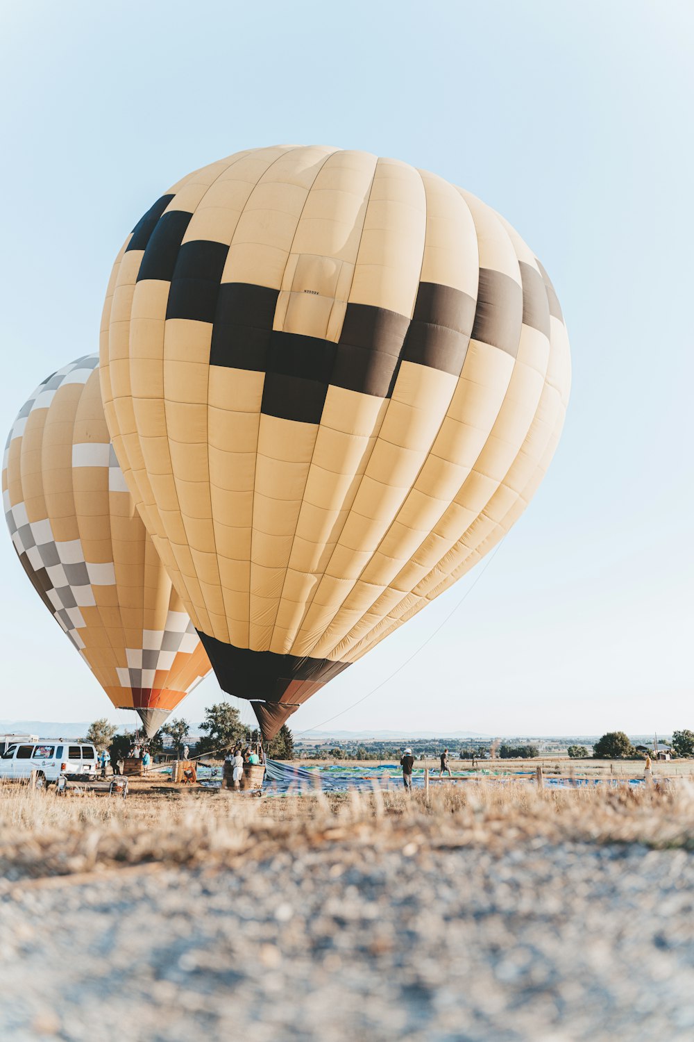 person in white shirt and blue denim jeans standing beside yellow and green hot air balloon