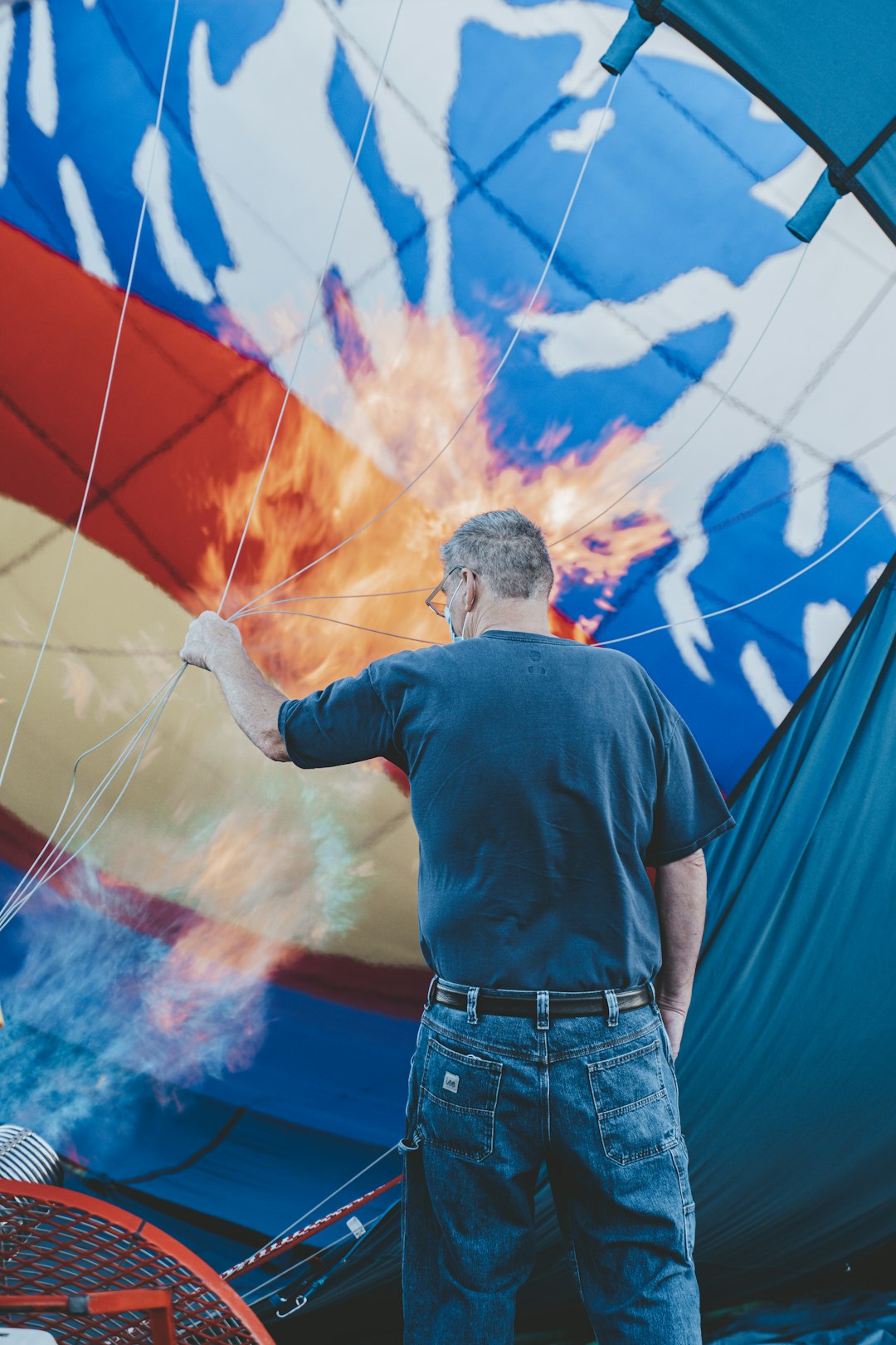 man in black shirt and blue denim jeans standing in front of blue and red hot