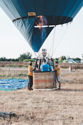 A hot air balloon preparing for takeoff in a green alpine meadow.