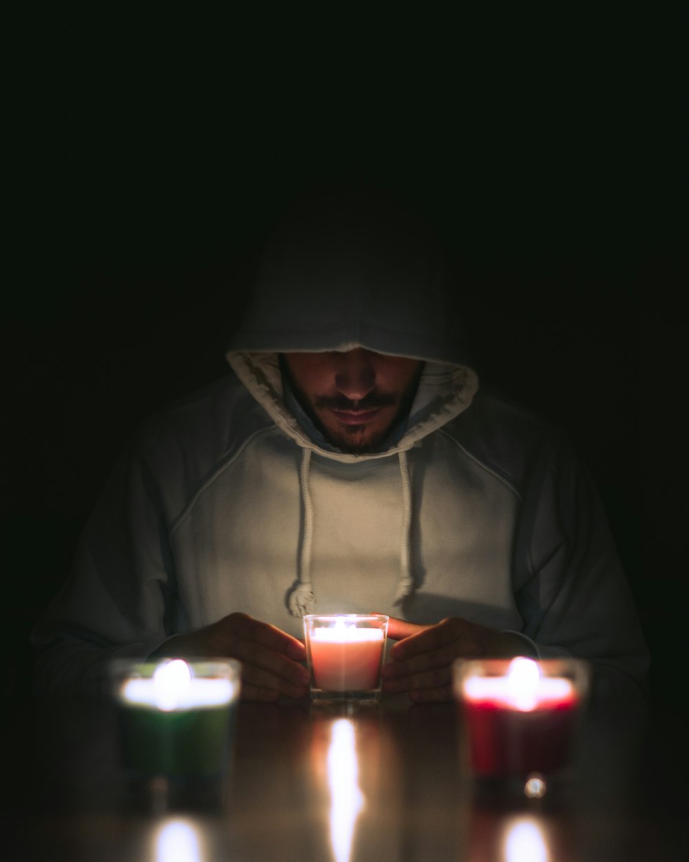 man in gray hoodie standing near lighted candles