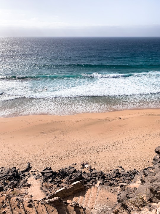 brown sand near body of water during daytime in Fuerteventura Spain