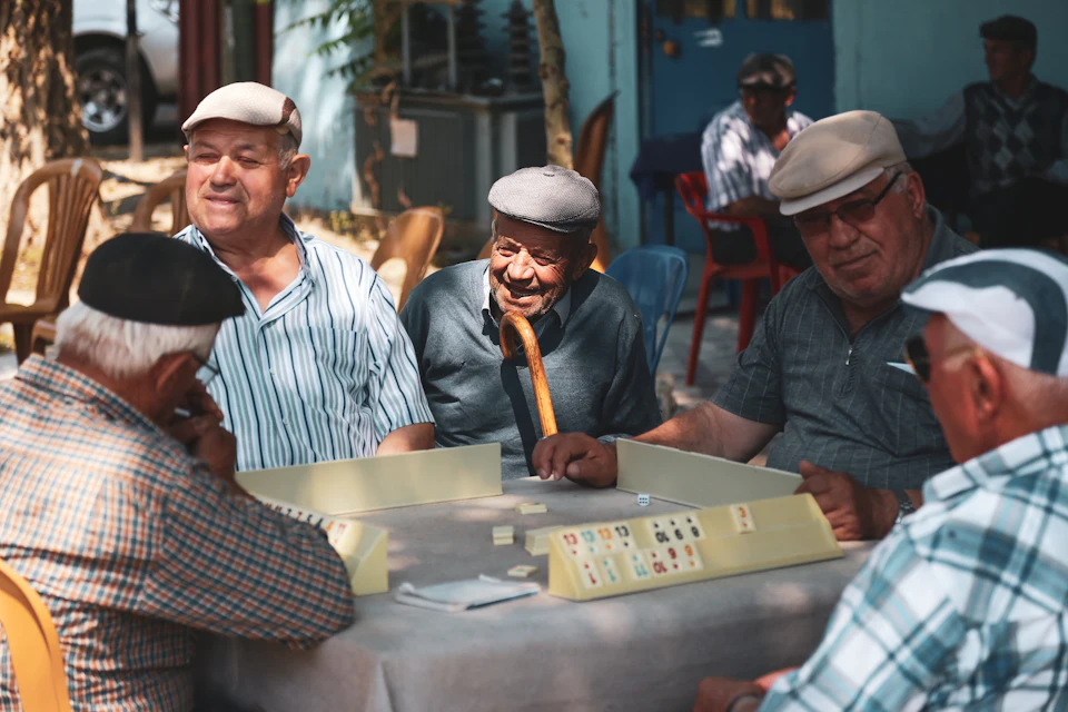 Older friends laughing over a game of dominoes