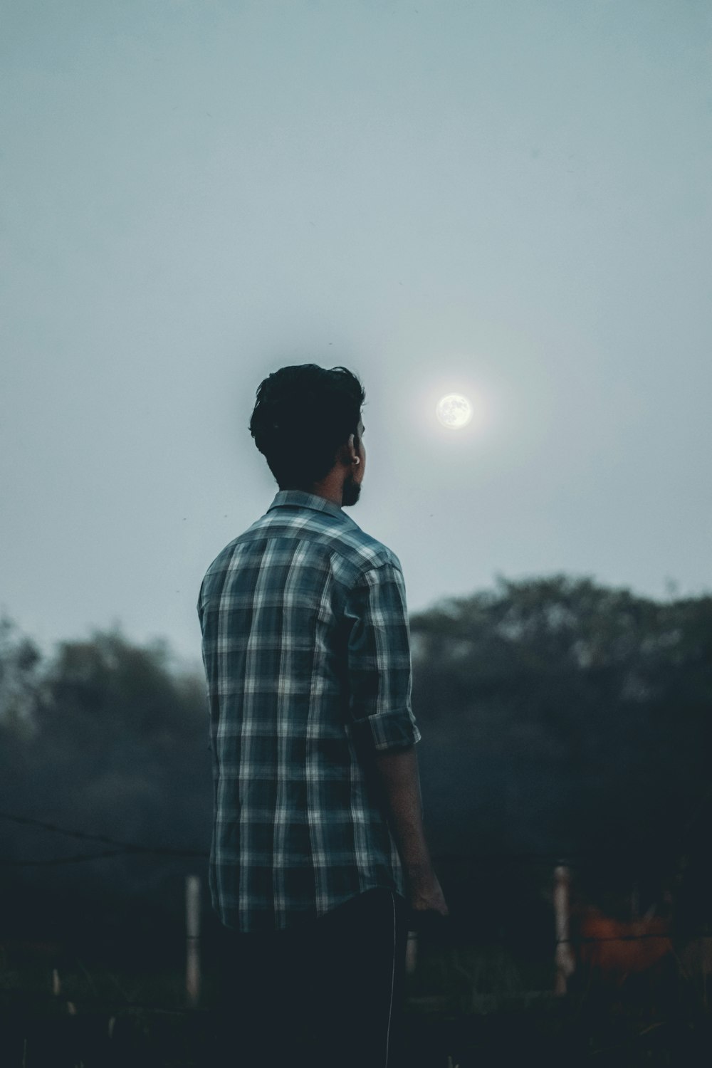 man in blue and white plaid button up shirt standing during daytime