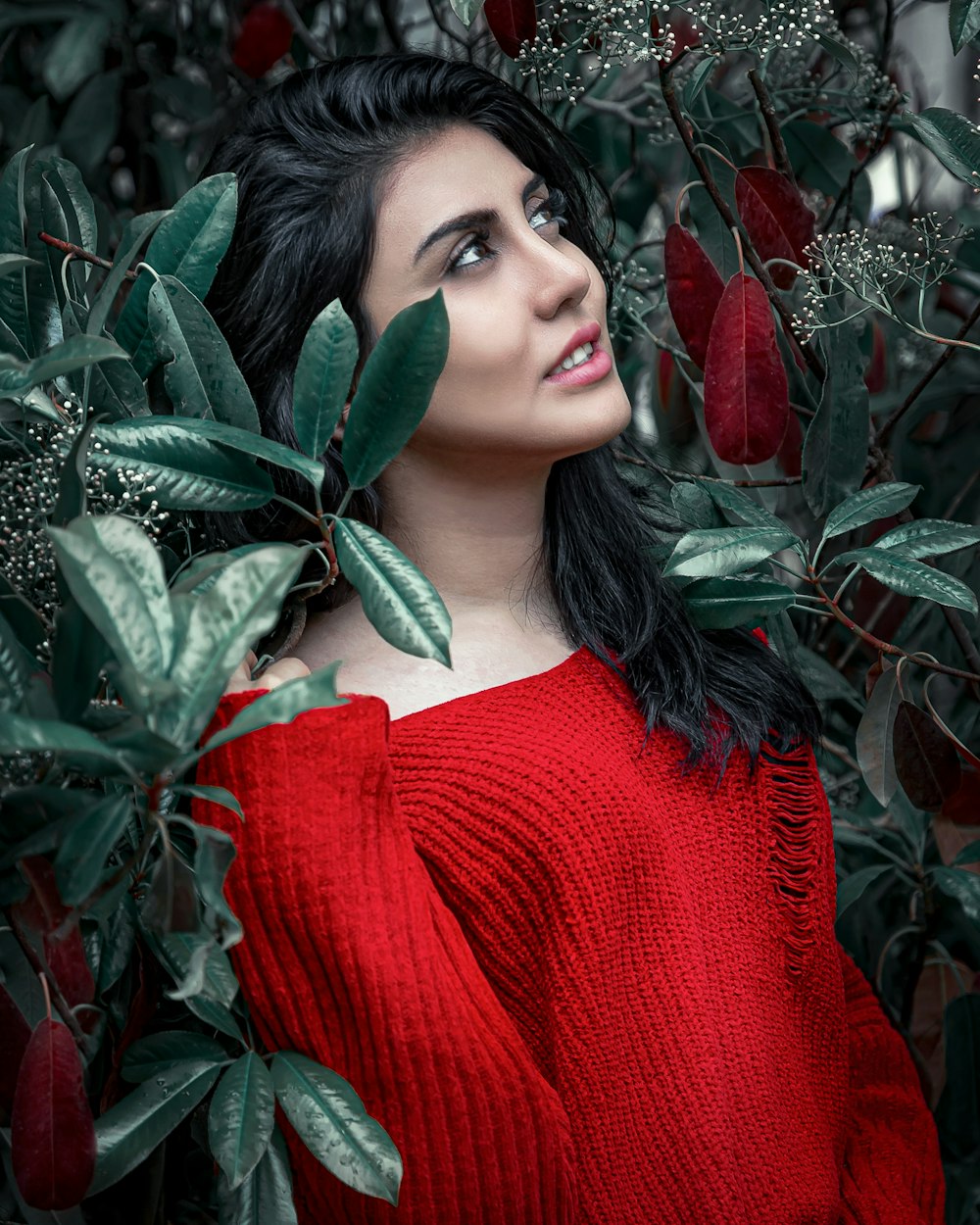woman in red knit sweater holding green leaves