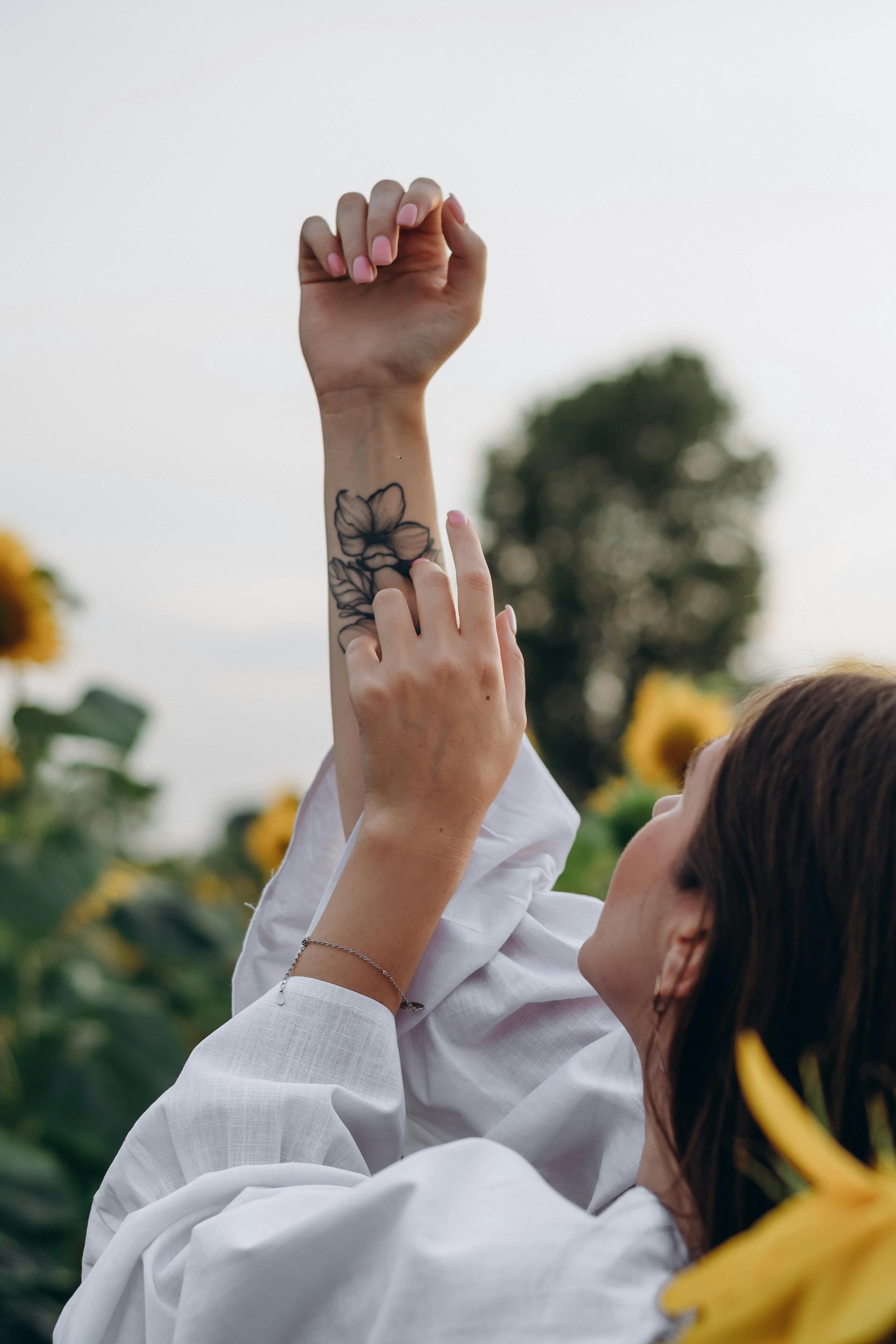woman with black and white floral tattoo on left hand