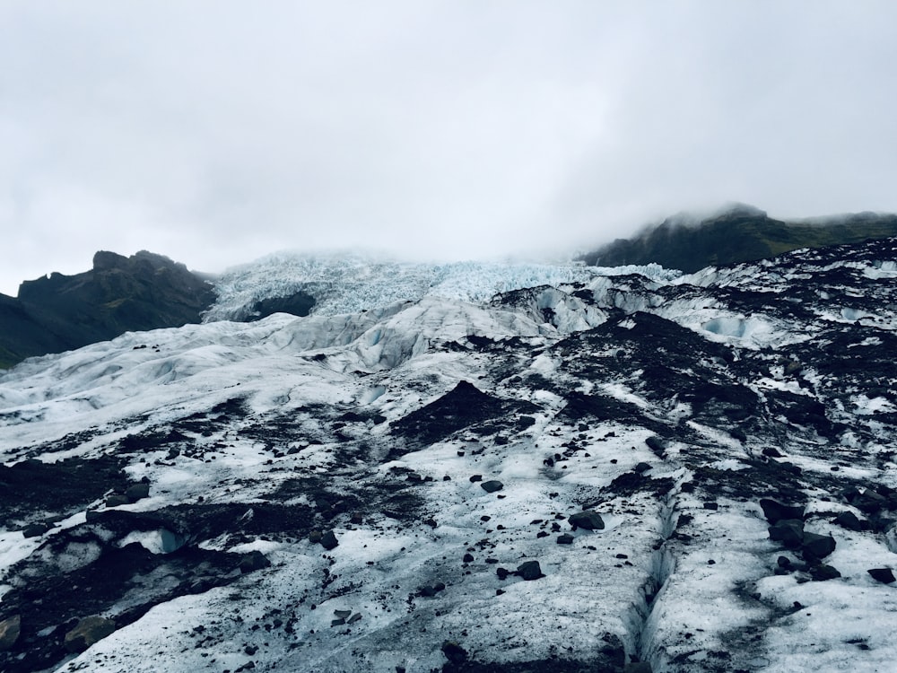 Schneebedeckter Berg tagsüber unter weißen Wolken