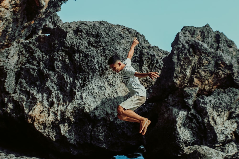 man in white t-shirt climbing on rocky mountain during daytime