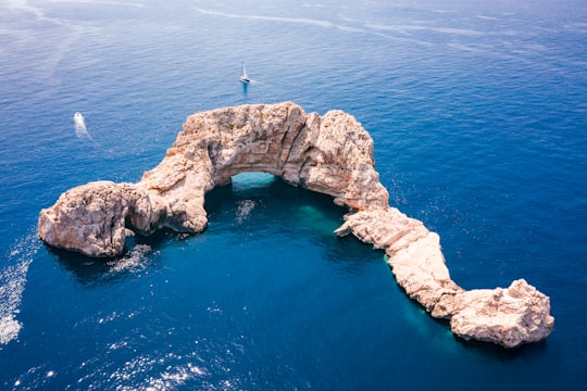 person standing on rock formation in the middle of the sea during daytime in Ibiza Spain