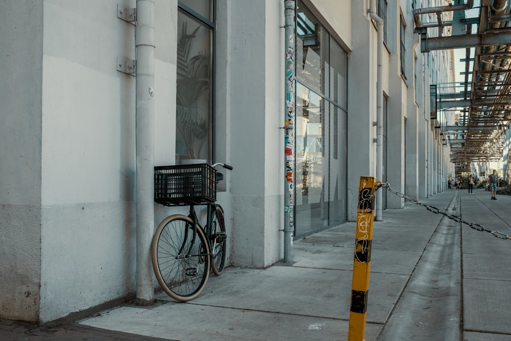 black bicycle parked beside gray concrete building during daytime