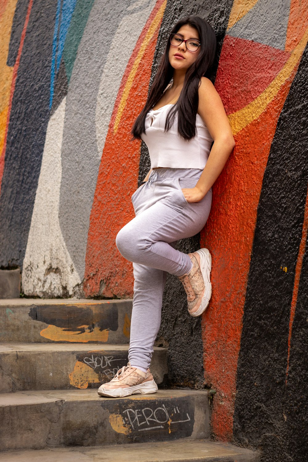 woman in white tank top and white pants sitting on concrete wall