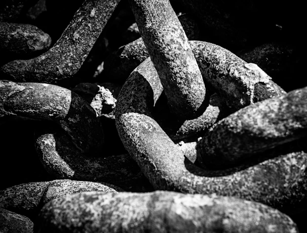 Close-up of intertwined ropes and chains against a dark backdrop, highlighting texture and contrast.