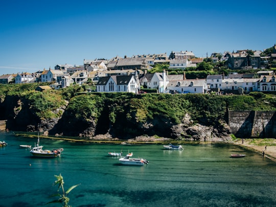 white and green boat on water near white concrete building during daytime in Port Isaac Bay United Kingdom