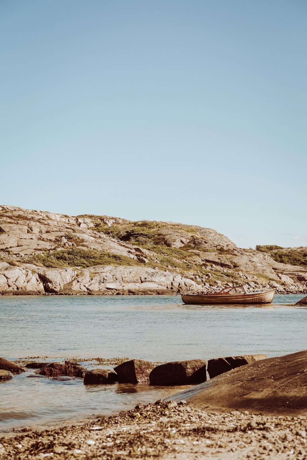 brown boat on sea near brown rock formation during daytime