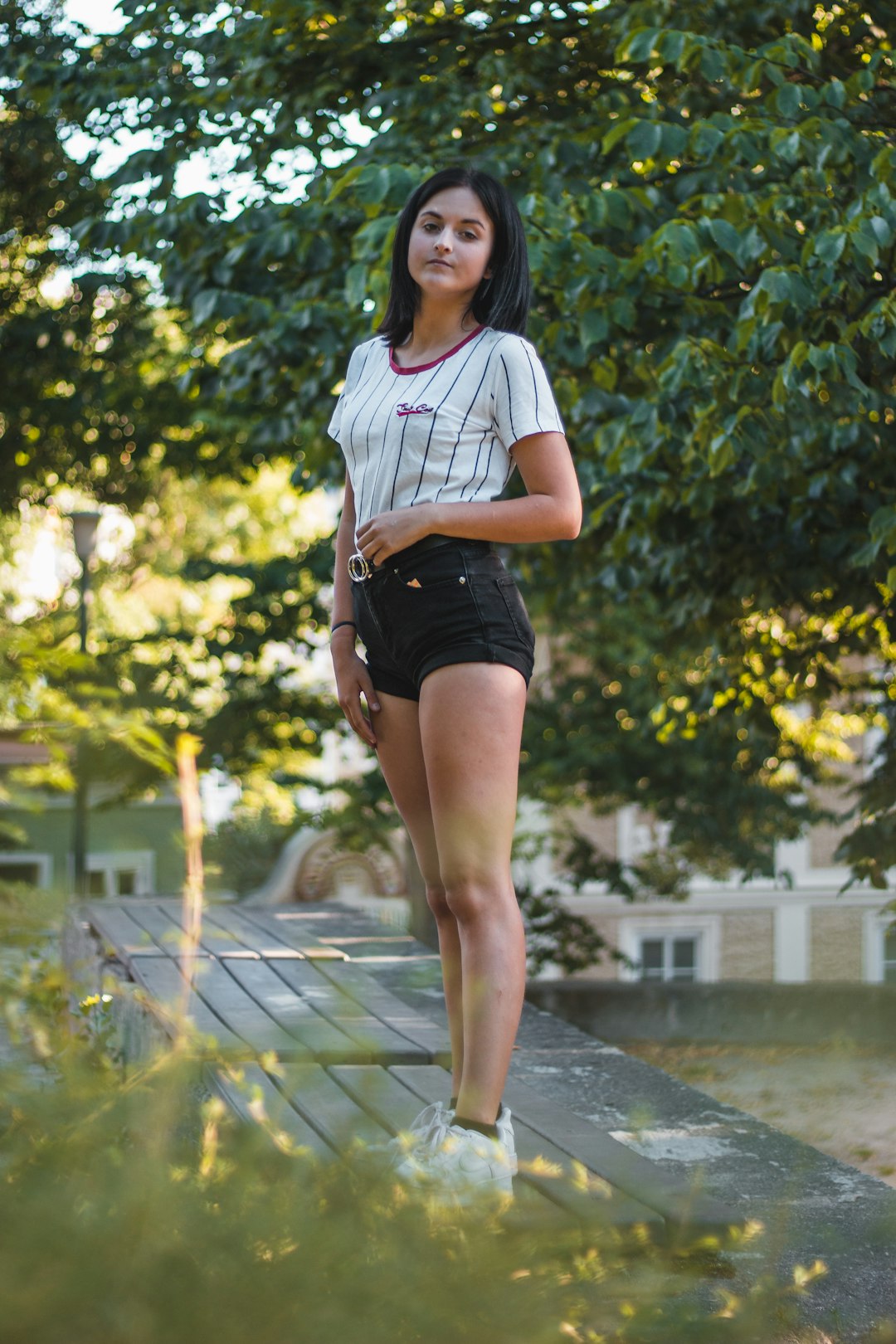woman in white and black t-shirt and black shorts standing on water fountain during daytime