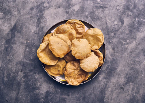Close-up of crispy golden urad papad stacked neatly on a rustic wooden board.