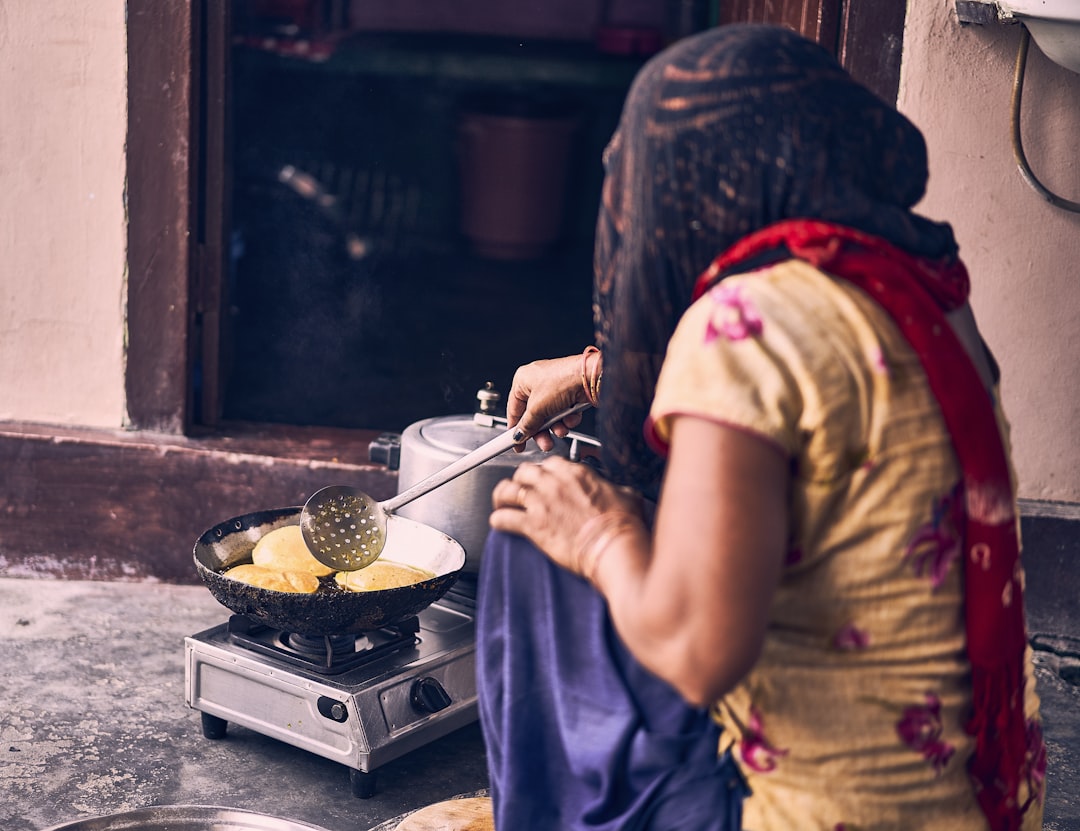 woman in brown shirt holding stainless steel cooking pot, A woman in ghoonghat cooking Pooris