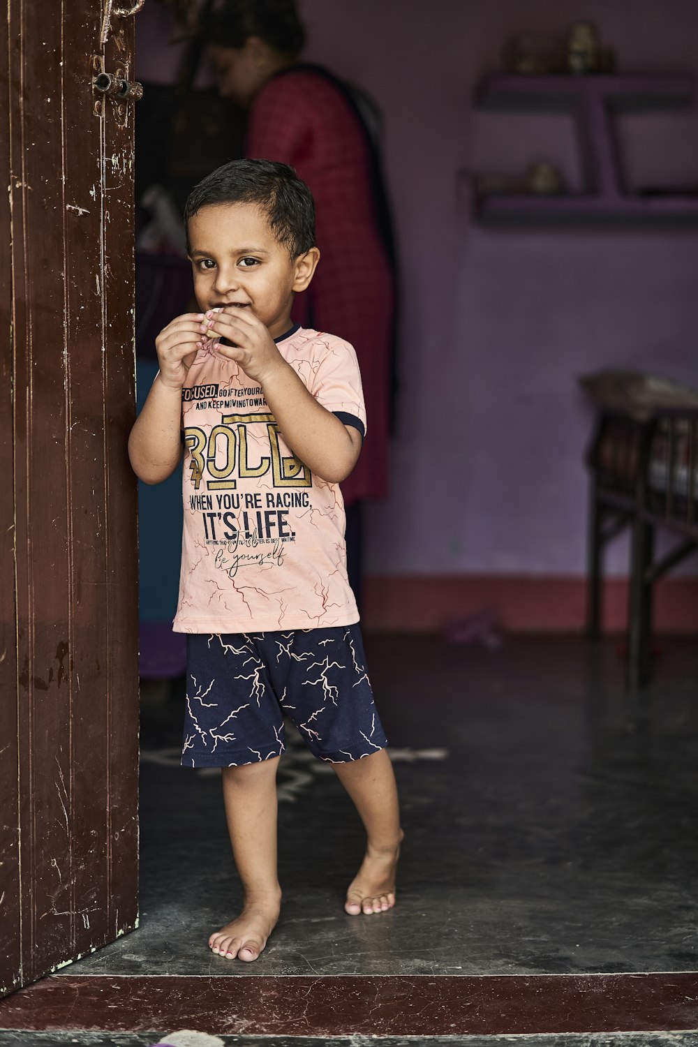 boy in red t-shirt and blue shorts standing