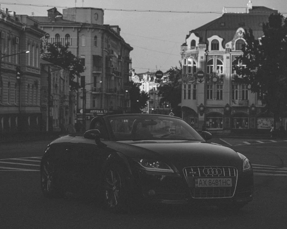 A modern sedan taxi parked on a quiet city street with soft evening lights.