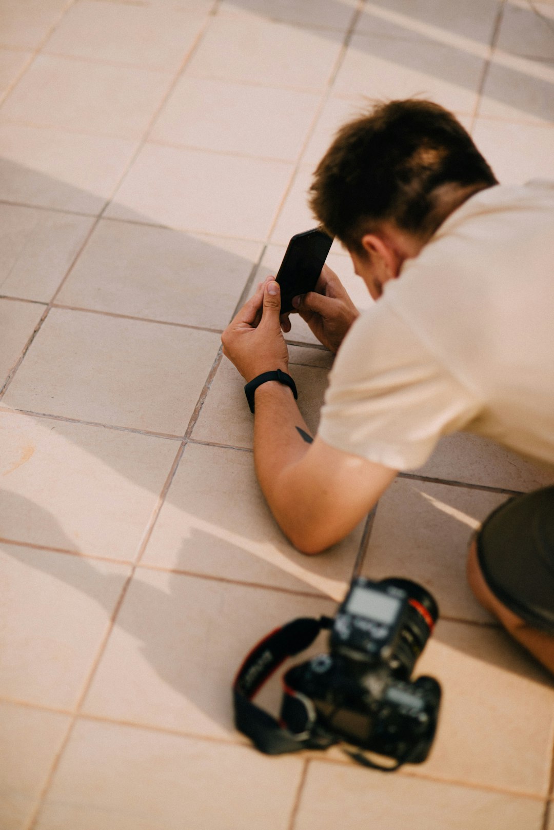 man in white t-shirt using black smartphone