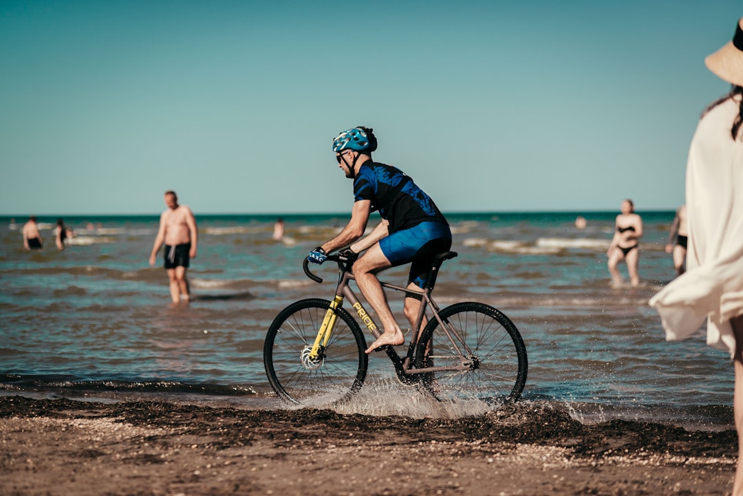 man in black jacket riding on bicycle on beach during daytime