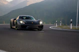 Side profile of the Mach1 GT speeding along a winding mountain road at sunset.
