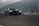 A close-up of a sleek mach1 performance car speeding along a winding mountain road at sunset.
