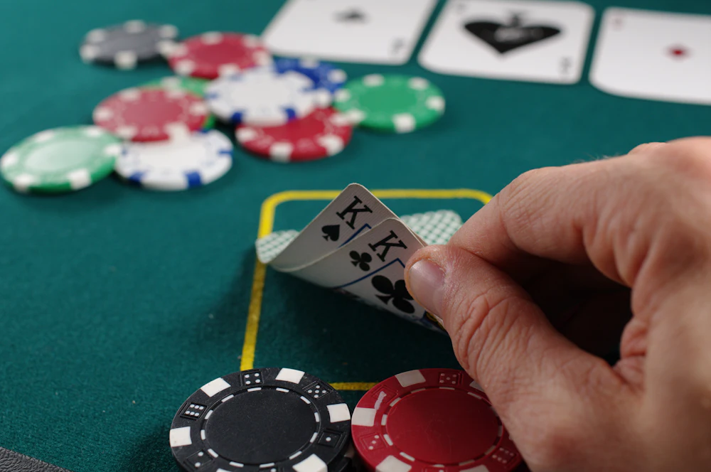 Pemain poker menyusun kartu remi di atas meja, menggambarkan pengambilan keputusan dalam permainan