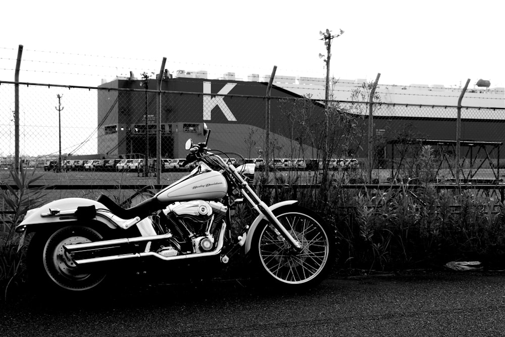 grayscale photo of motorcycle parked beside wall