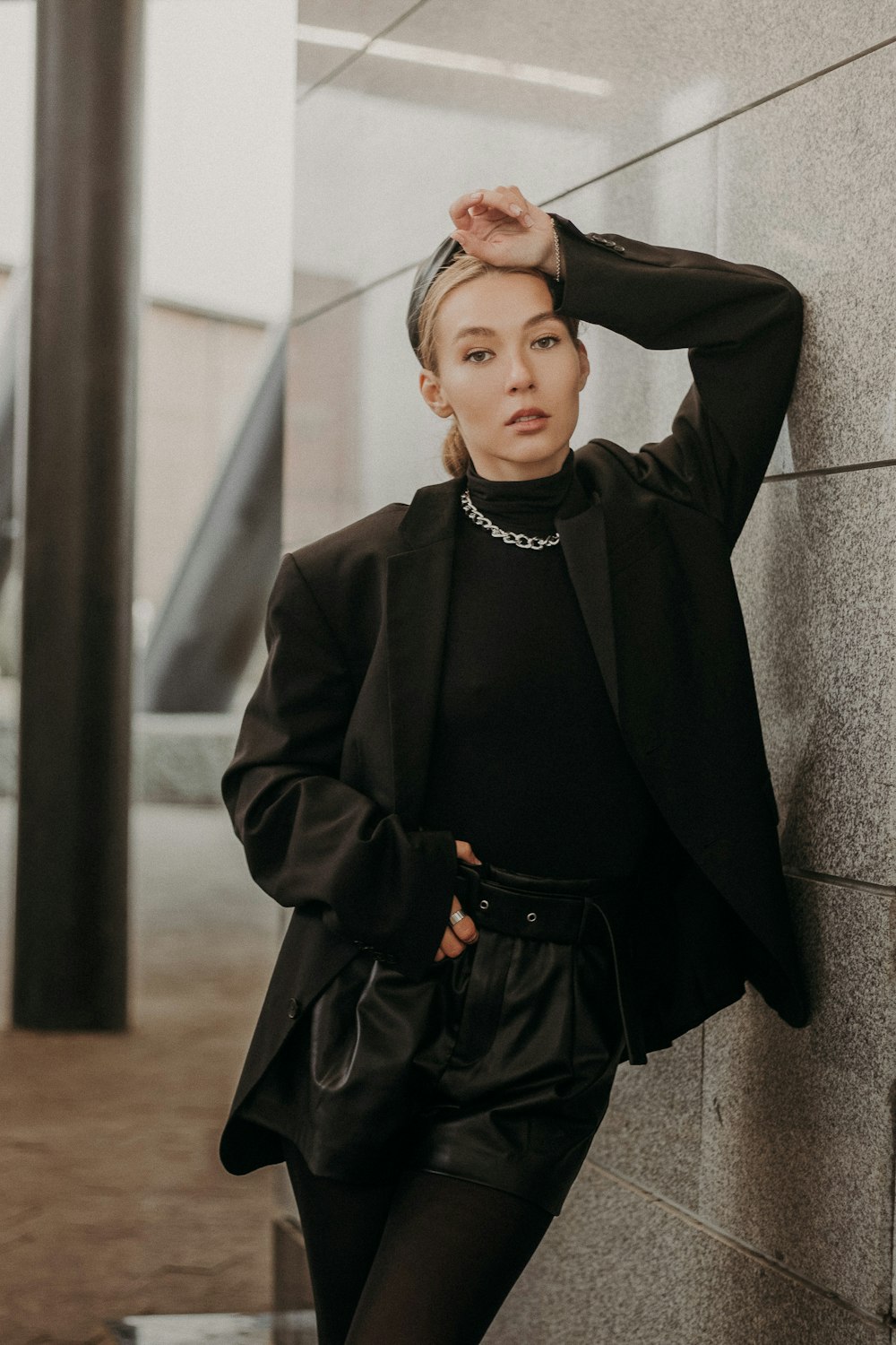 woman in black coat standing near gray concrete wall during daytime