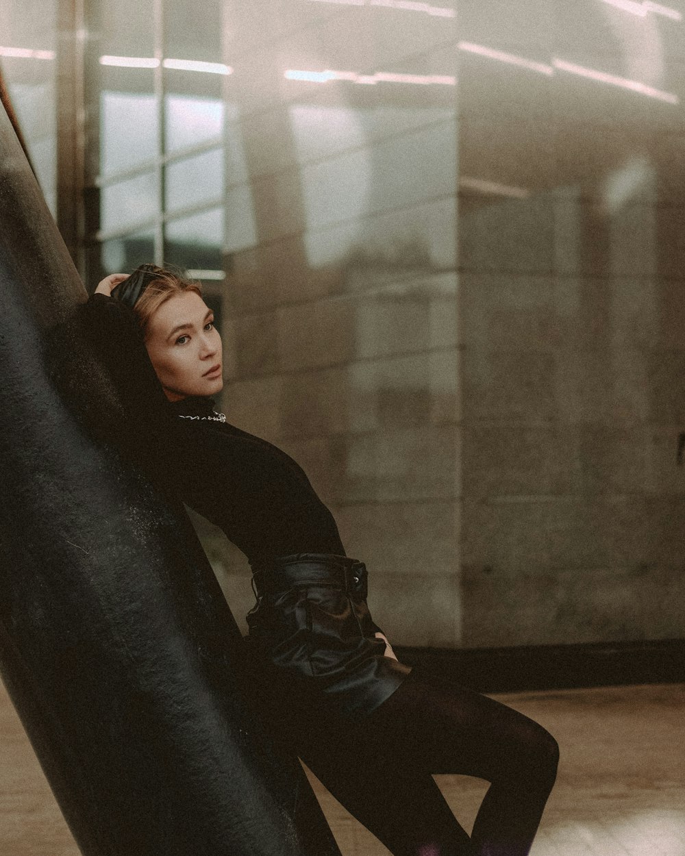 woman in black long sleeve shirt leaning on black leather couch