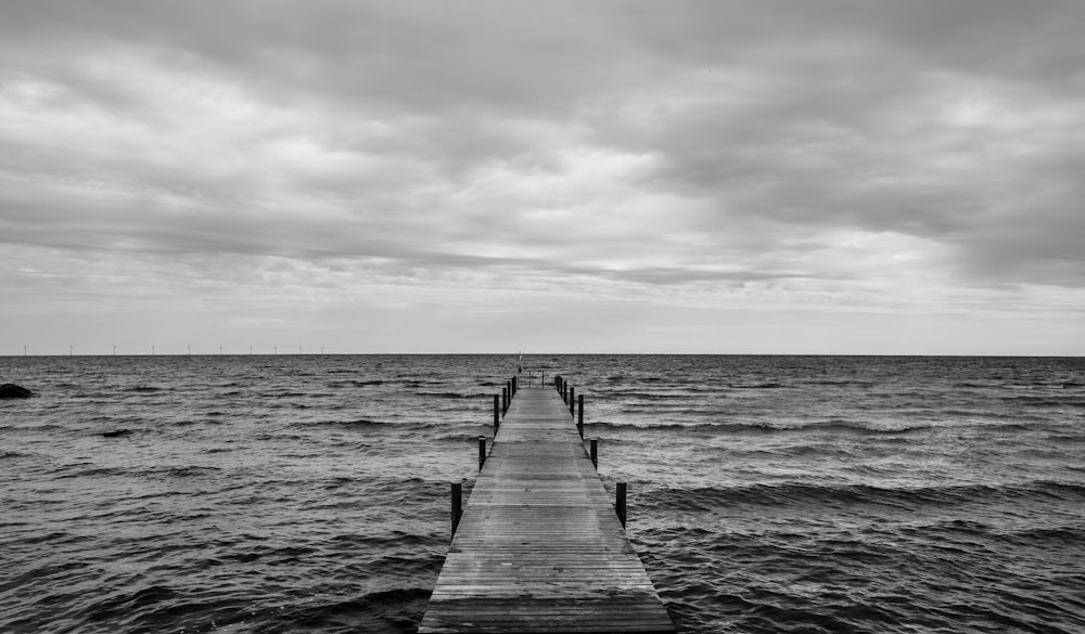 grayscale photo of wooden dock on sea