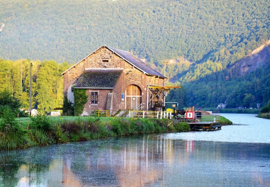 brown wooden house near lake and mountain during daytime in Fumay France