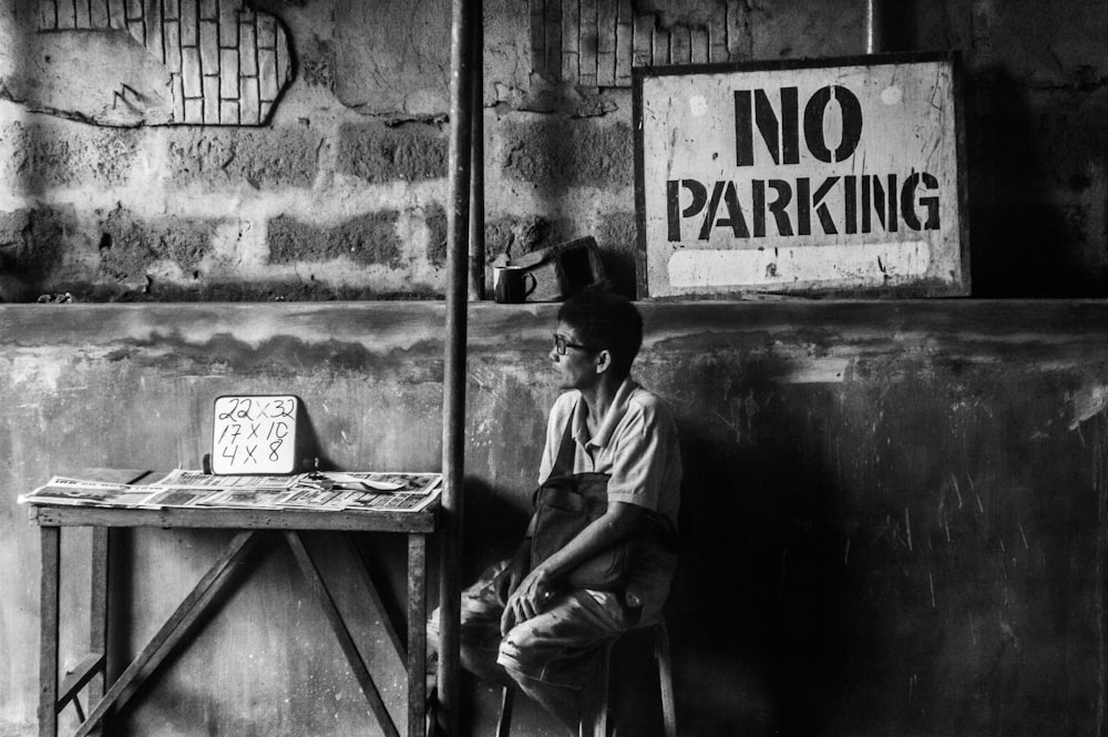 grayscale photo of man sitting on chair