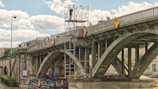 people riding on blue and black motorcycle under gray bridge during daytime