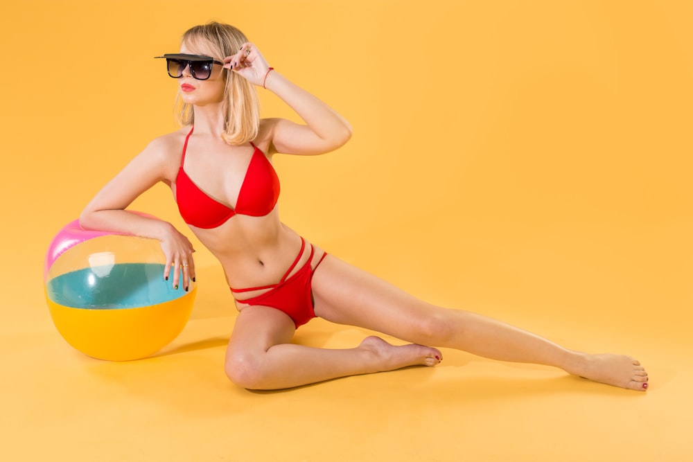 Mujer en bikini rojo acostado en anillo inflable amarillo