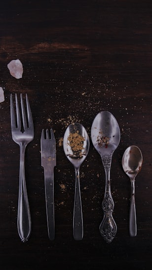 stainless steel spoons and fork on brown wooden table