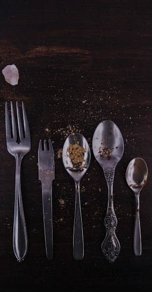 stainless steel spoons and fork on brown wooden table