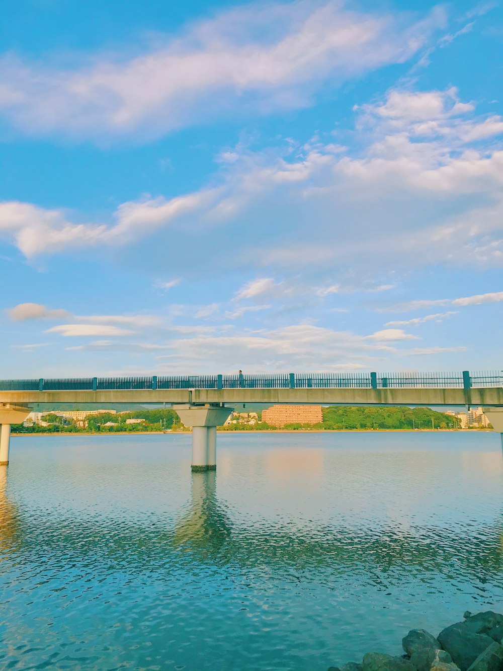 gray concrete bridge over river under blue sky during daytime