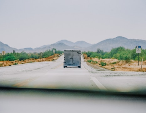A cargo truck driving on a highway surrounded by green landscapes.