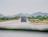 A truck driving on a highway surrounded by green fields.