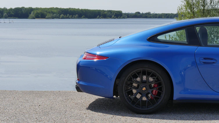 A gleaming car parked by the ocean under a bright blue sky, showcasing a flawless shine.