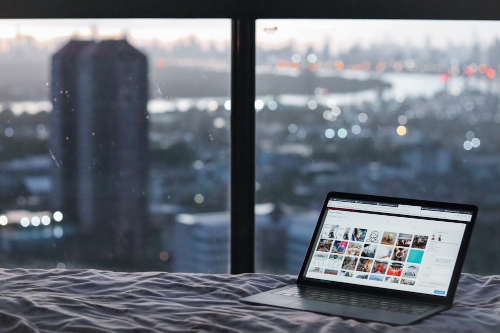 black laptop computer on white bed linen