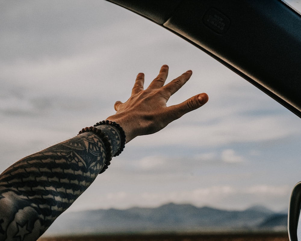 person in black and white long sleeve shirt raising left hand