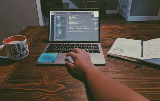 A friendly professional working on a laptop with code and design sketches around.